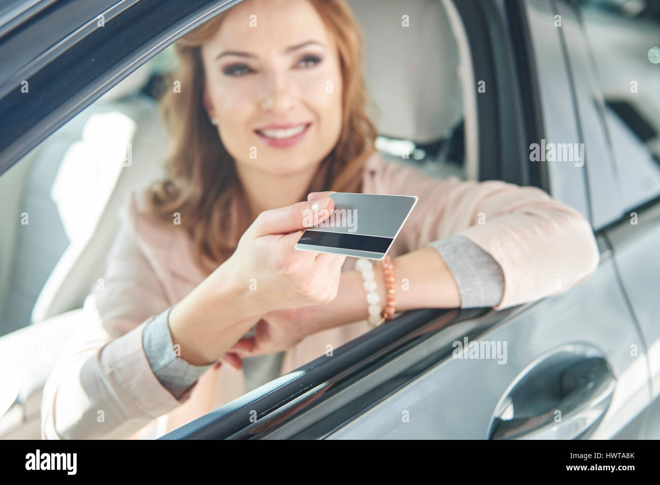 Donna seduta in un auto con carta di credito Foto Stock