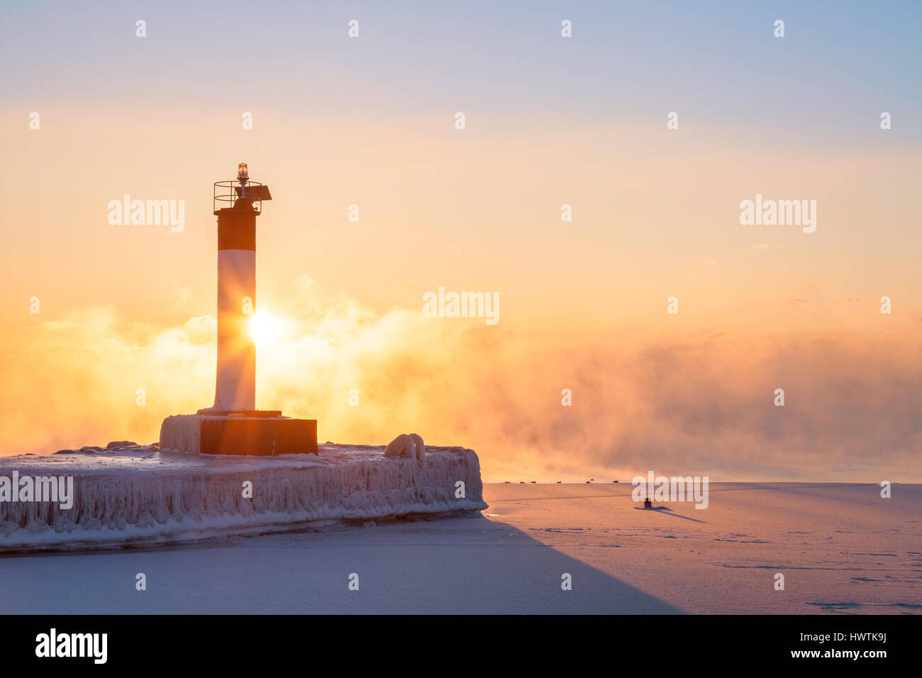 Un faro di sunrise su un molo su un freddo inverno mattina con pesanti lago di nebbia. Oakvile, Ontario, Canada. Foto Stock