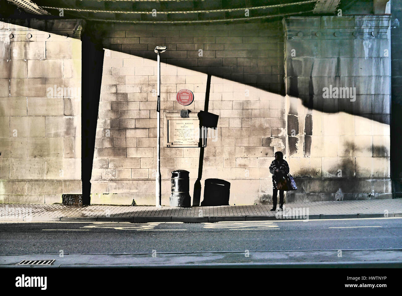 La donna in attesa di autobus al di sotto dello Yorkshire acquedotto street,Burnley,Lancashire, Regno Unito Foto Stock