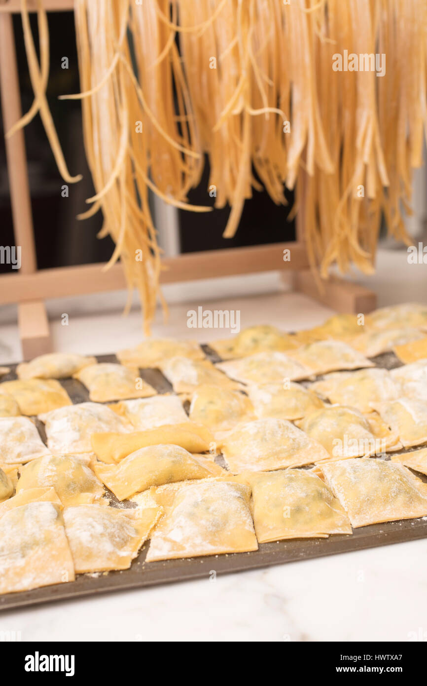 Spaghetti fatti in casa essiccazione su un rack di pasta e ravioli pronti per essere cucinati Foto Stock