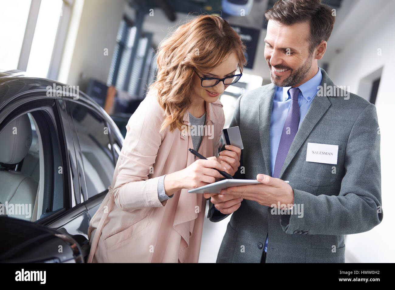 Donna firma accordo per auto nello showroom Foto Stock