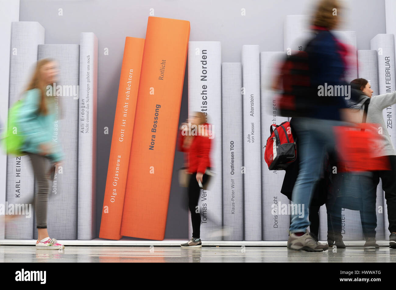 I visitatori a piedi da una parete con una grande immagine di libri nella fiera del libro di Lipsia, Germania, 23 marzo 2017. A partire dal 23 marzo Leipzig sarà ancora una volta diventato la mecca per gli autori e gli editori e gli appassionati di letteratura. Fino a domenica, 26 marzo 2017, oltre 3400 eventi avranno luogo in fasi 570. Il paese ospite è la Lituania. Il conteggio dei visitatori dello scorso anno è venuto fino a 260.000. Foto: Jens Kalaene/dpa-Zentralbild/dpa Foto Stock