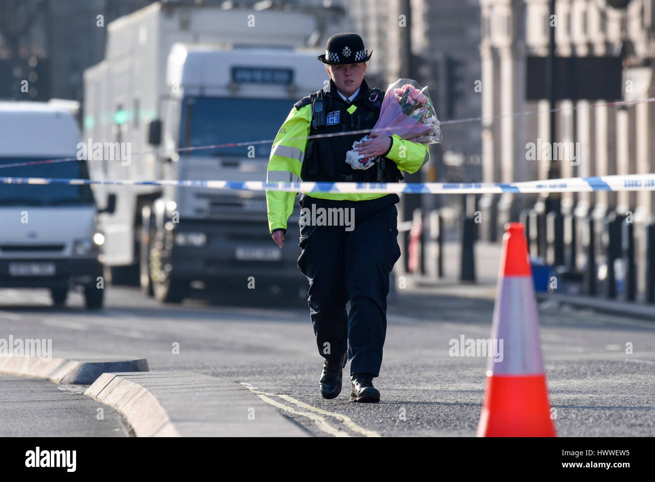 Londra, Regno Unito. Il 23 marzo 2017. Una poliziotta arriva a gettare fiori come segno di rispetto al di fuori della casa del Parlamento, seguendo ieri in attacco terroristico a Westminster. Credito: Stephen Chung / Alamy Live News Foto Stock