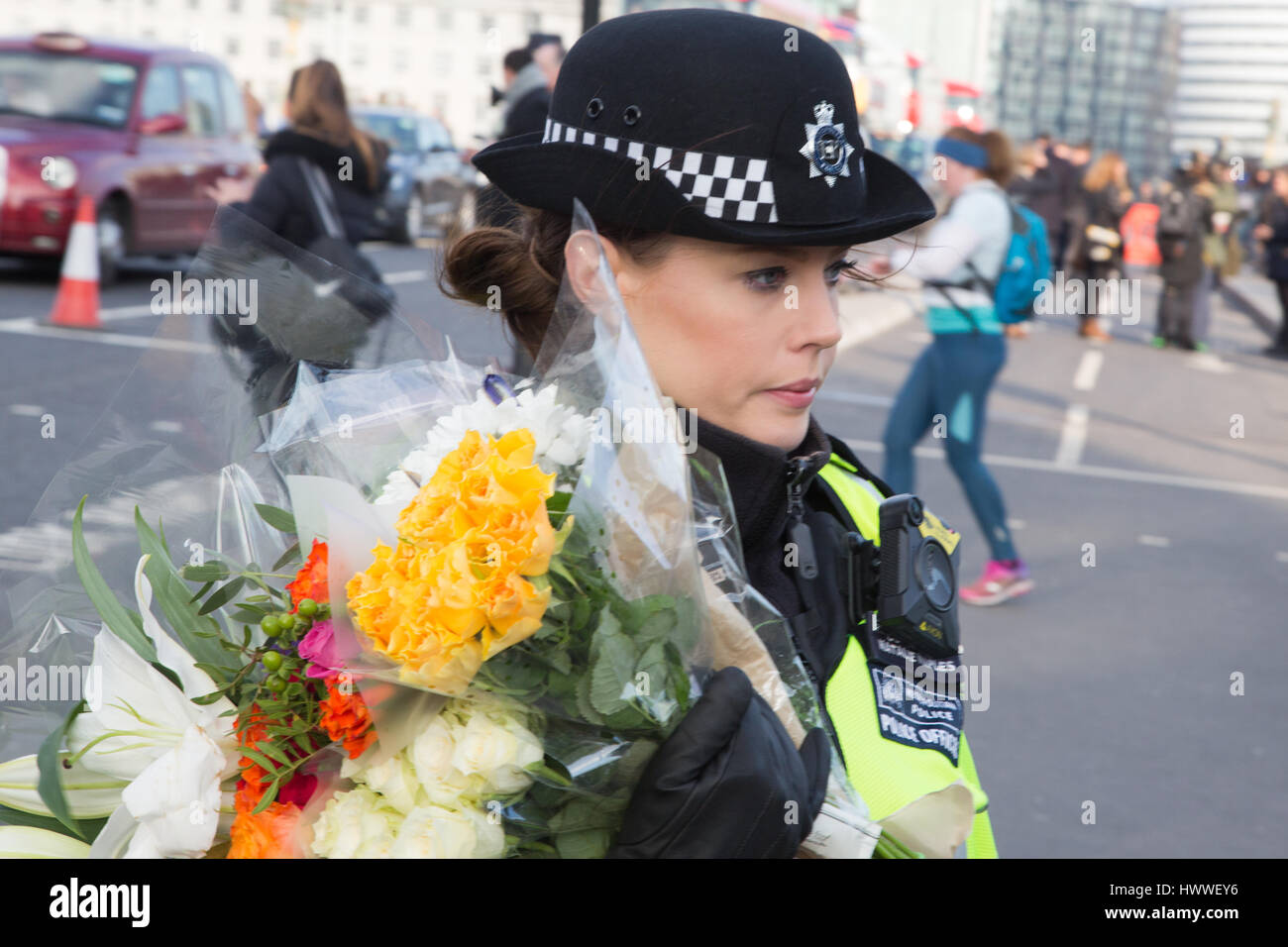 Londra 23 marzo 2017 una poliziotta stabilisce omaggio floreale al di fuori del palazzo di Westminster a seguito ieri in un attacco in cui un funzionario di polizia è stato ucciso. Foto Stock