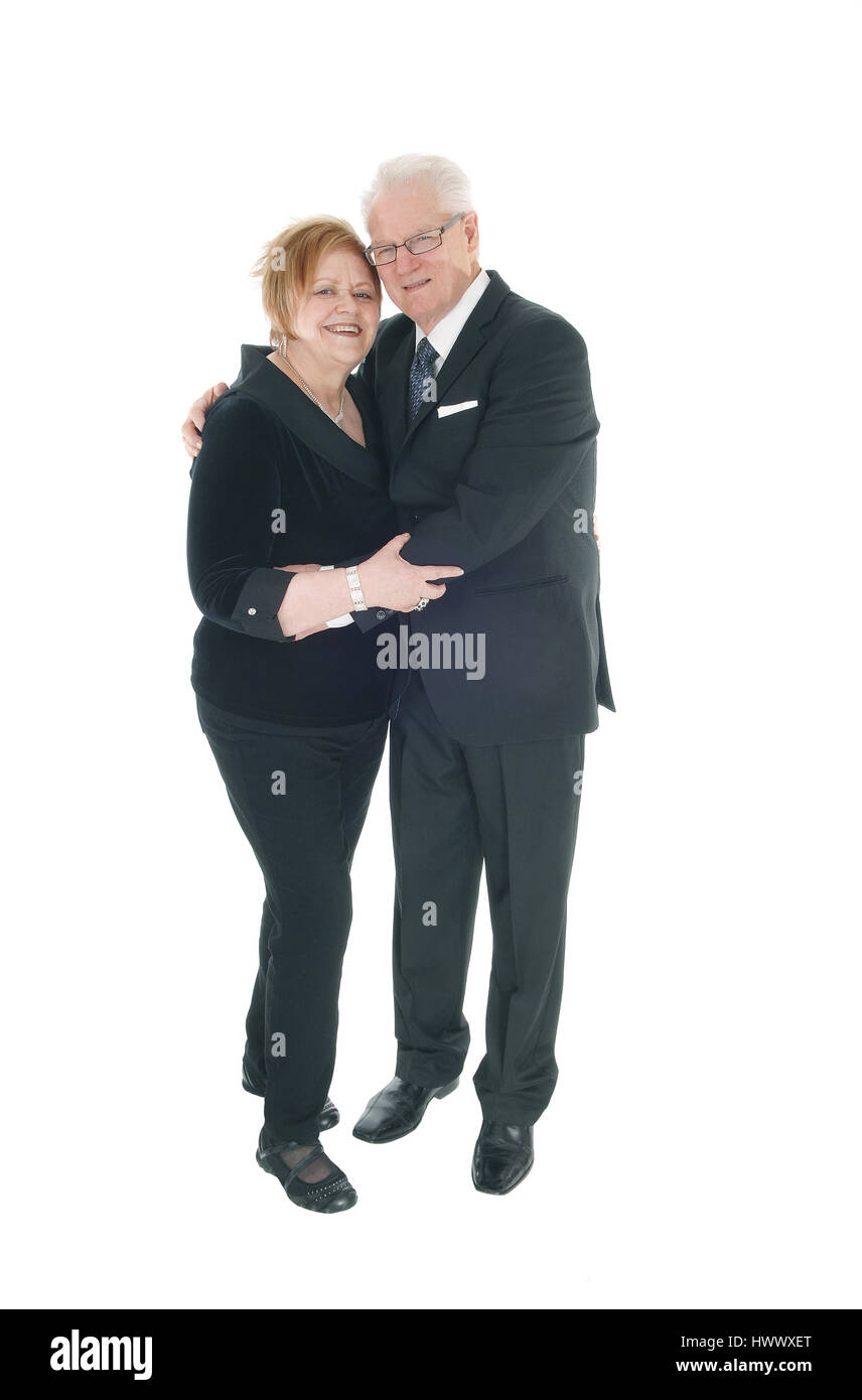 Una bella coppia di anziani in piedi in abiti, abbracciando ogni altro in lunghezze completo isolato per sfondo bianco. Foto Stock