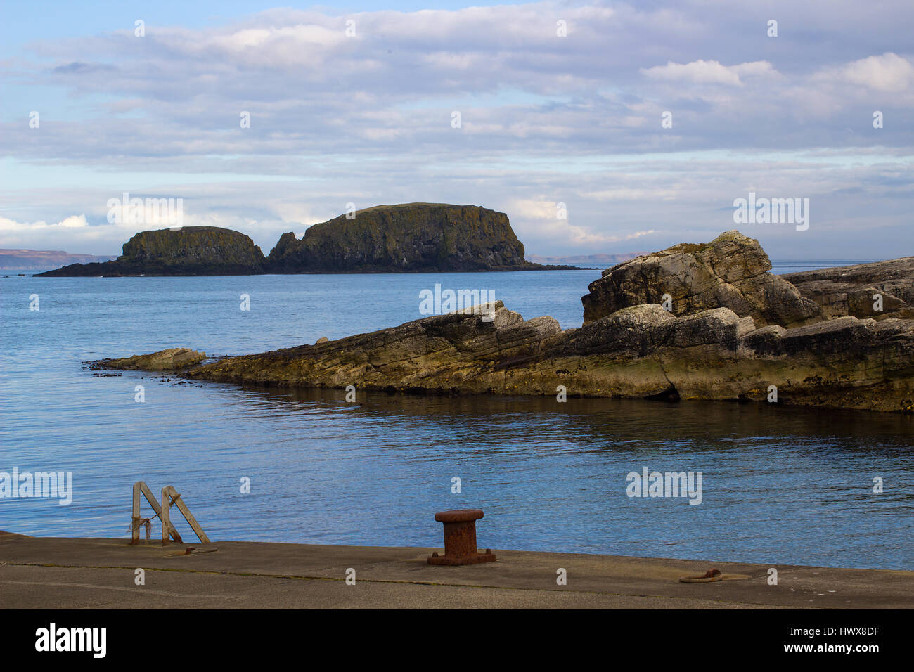 Il Rocky ingresso del piccolo porto di Ballintoy sulla costa North Antrim dell Irlanda del Nord su una tranquilla giornata di primavera. Foto Stock