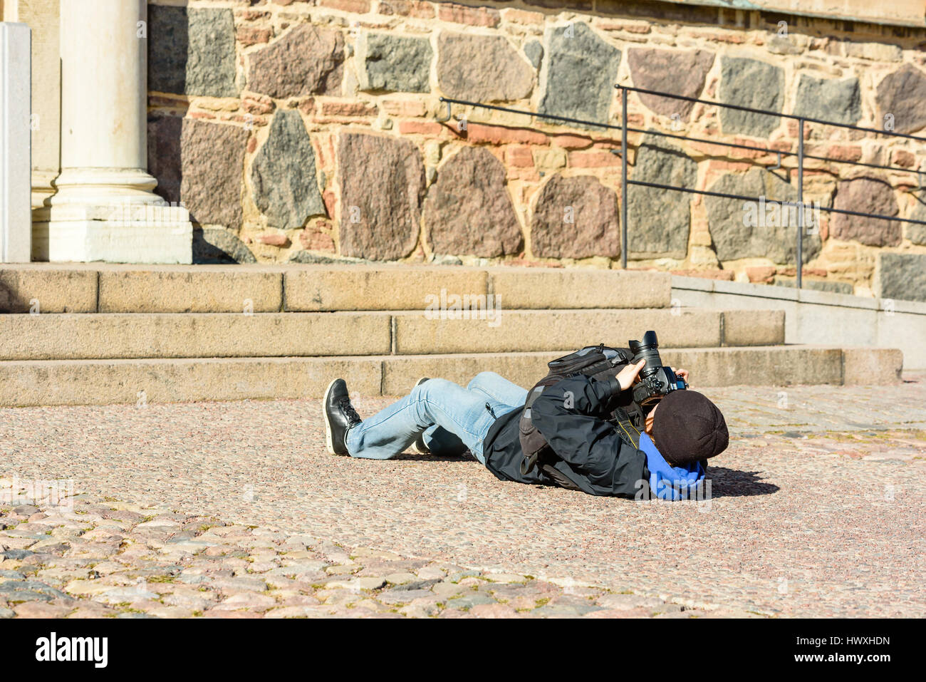 Fotografo sdraiato a terra mentre si fotografa un grande edificio da diverse prospettive. Fotografia creativa stile. Foto Stock