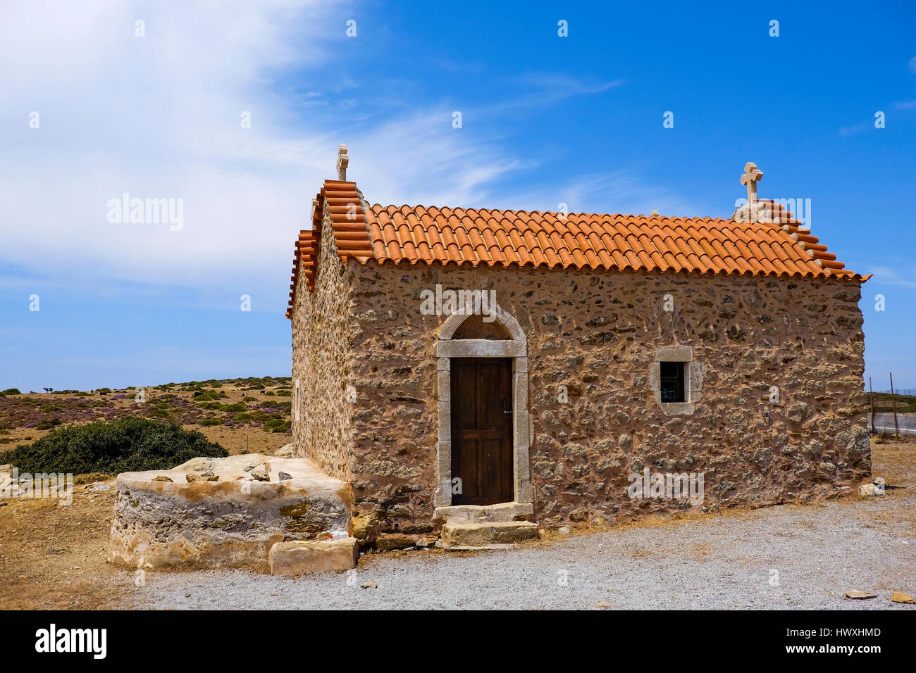 Chiesa di piccole dimensioni con piastrelle di colore arancione in piedi in un paesaggio deserto sull isola di Creta Grecia Foto Stock
