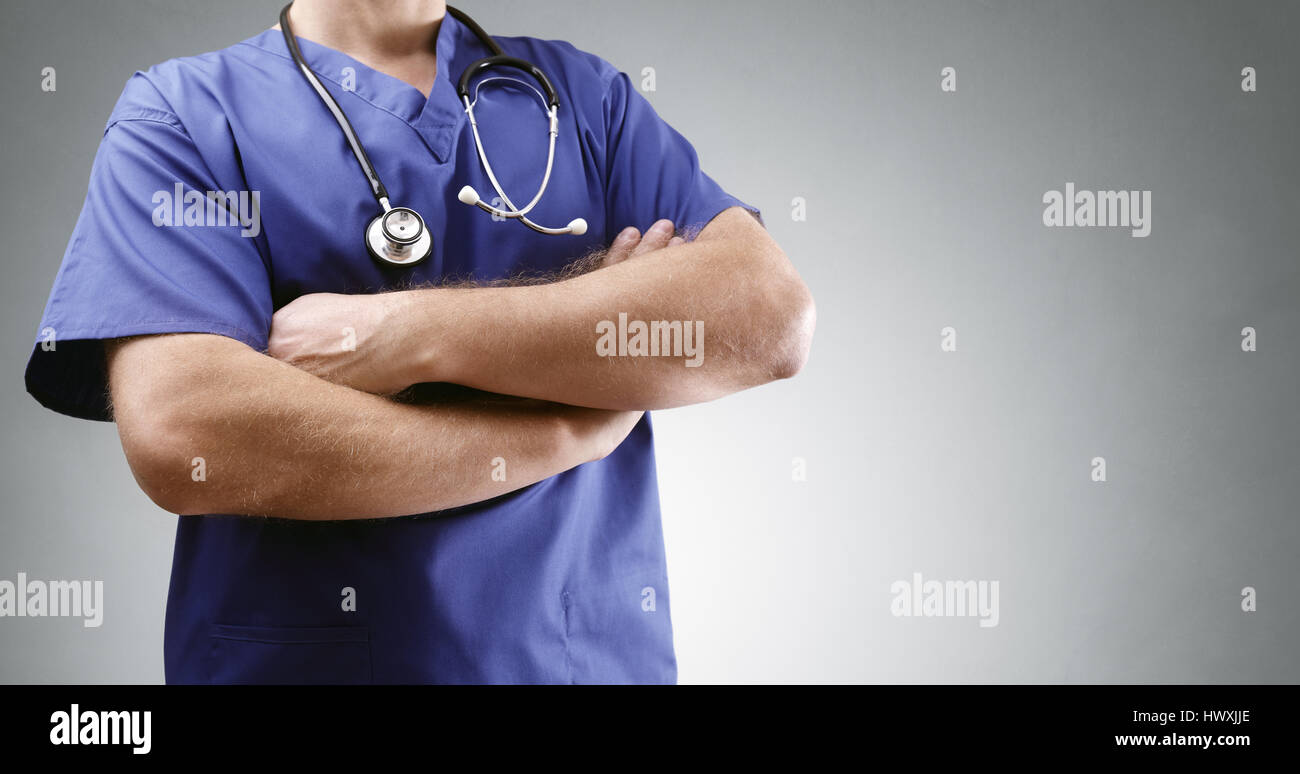Dottore in scrubs bracci pieghevoli con lo stetoscopio e lo sfondo grigio per la copia Foto Stock