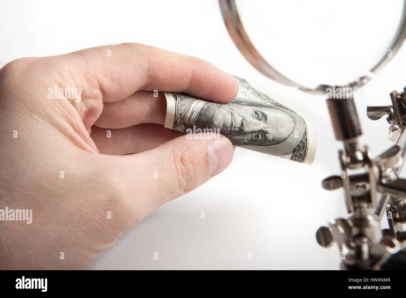 Ispettore delle finanze. Controlla i soldi per autenticità attraverso una lente di ingrandimento. Le mani di close-up. Foto Stock