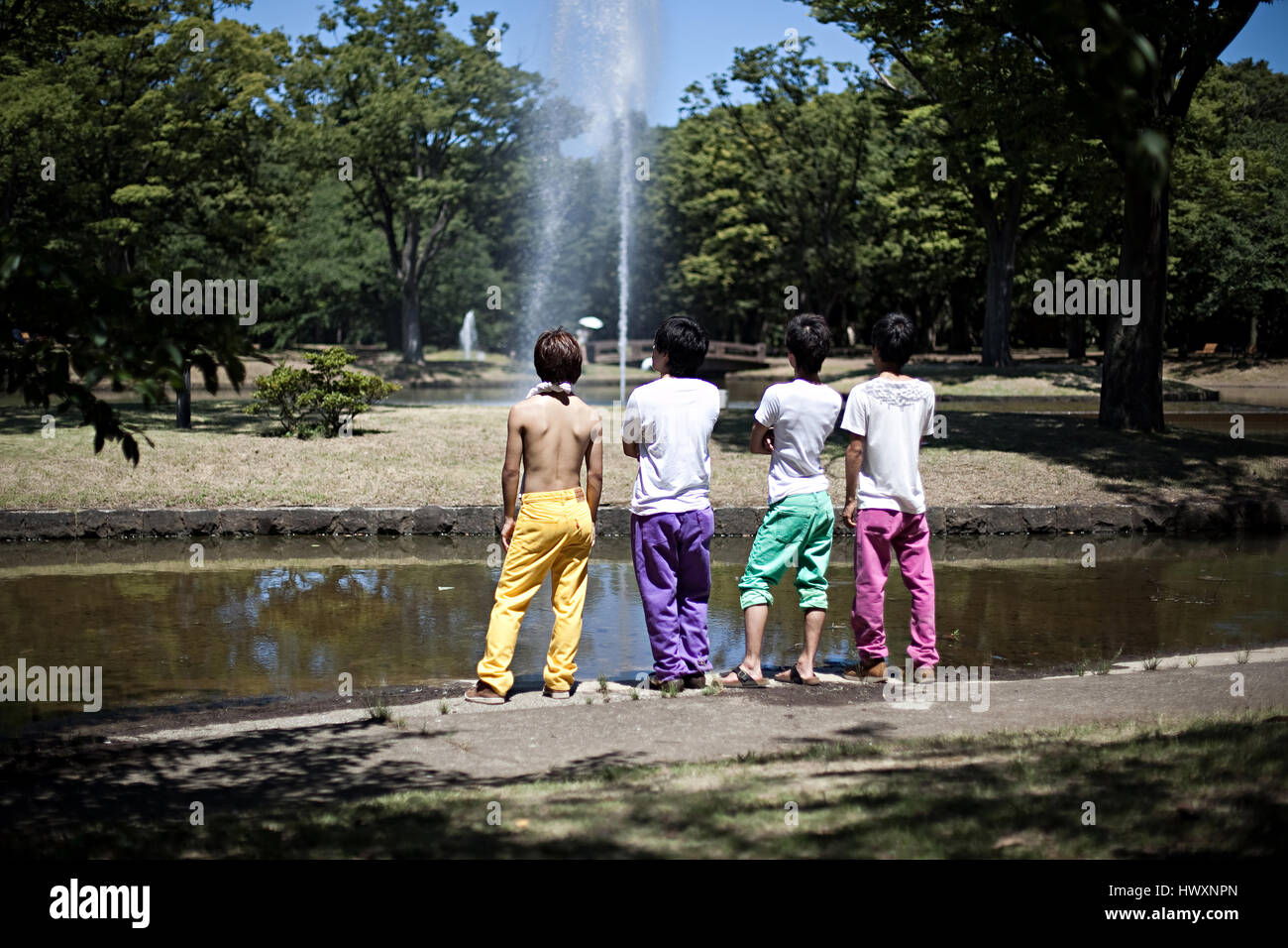 Quattro ragazzi giapponesi in pantaloni colorati guardando la fontana di acqua nel Yoyogi Park a Tokyo, Giappone. Foto Stock