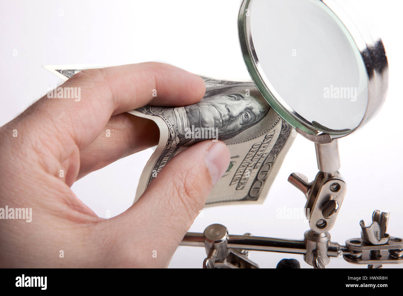 Ispettore delle finanze. Controlla i soldi per autenticità attraverso una lente di ingrandimento. Le mani di close-up. Foto Stock
