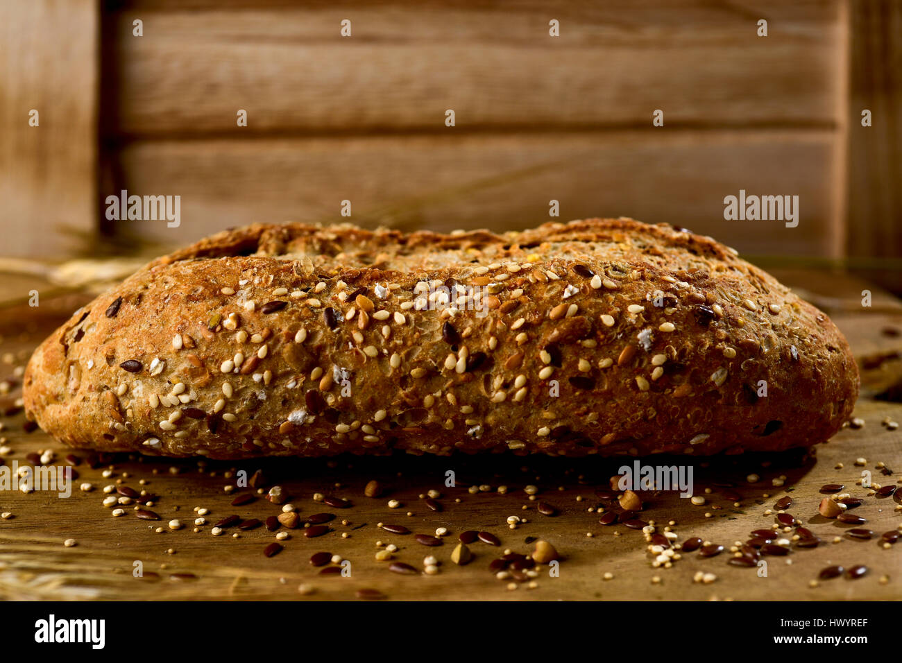 Primo piano di un pane integrale roll e rabboccato con diversi semi come il sesamo e semi di papavero, su una tavola in legno rustico Foto Stock