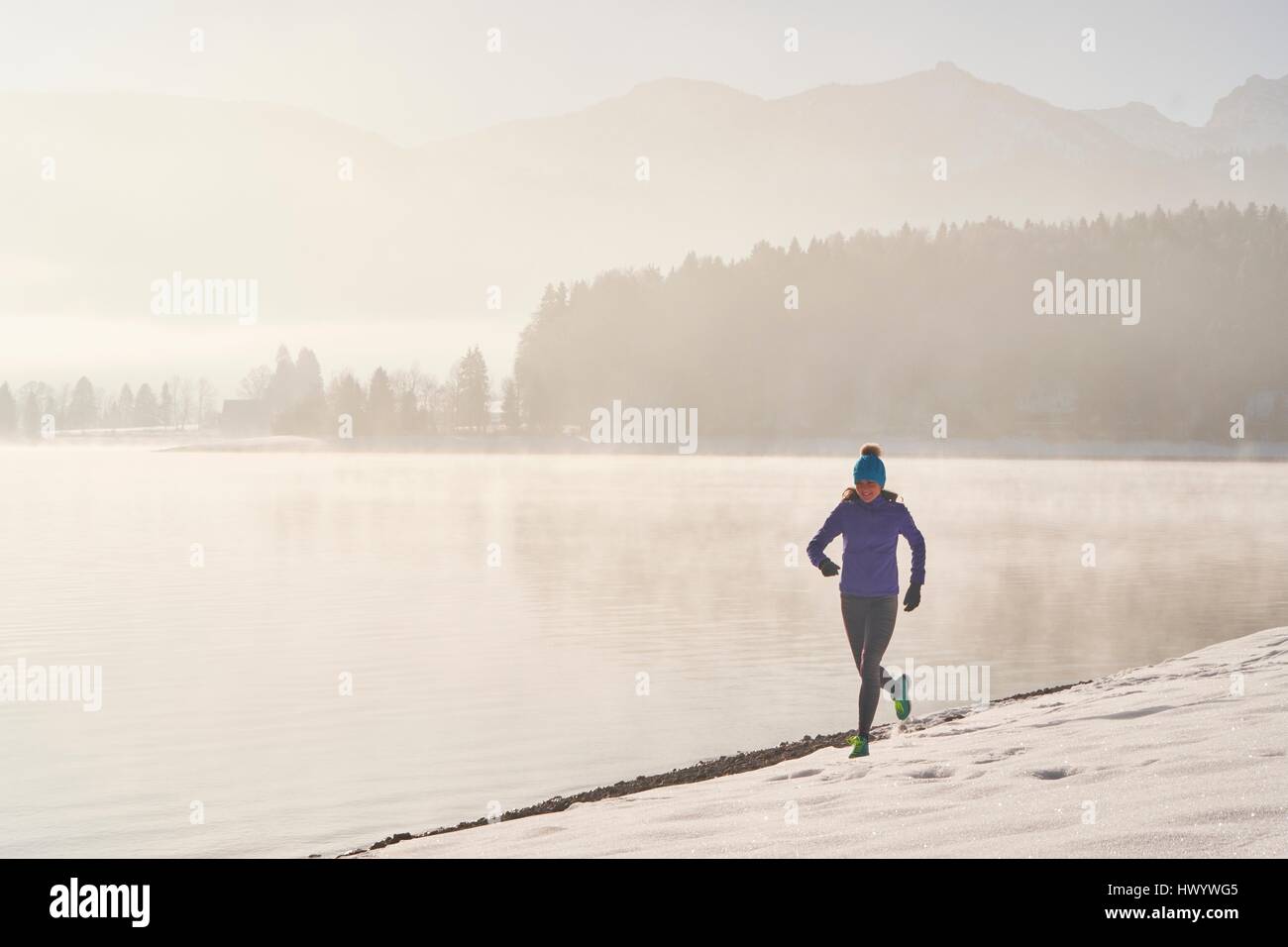 In Germania, in Baviera, Lago di Walchen, donna jogging in inverno Foto Stock