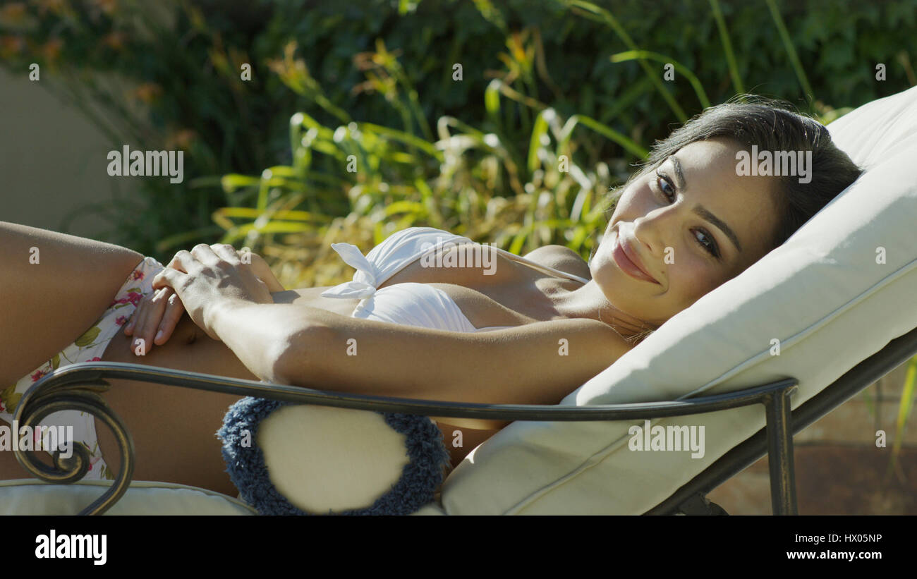 Ritratto di donna sorridente in bikini a prendere il sole e la posa sul prato sedia Foto Stock