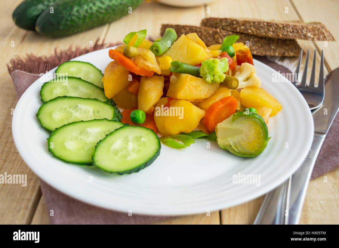 Stufato di vegetali (patate, asparagi, carote, i cavoli di Bruxelles, mais, piselli, cavolo verza, broccoli) in una piastra bianca. Vegane. Foto Stock