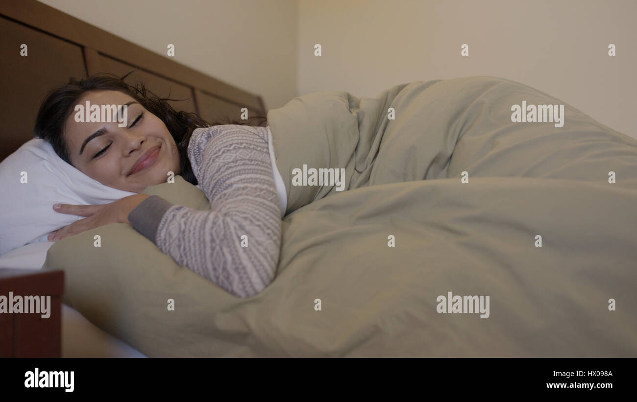 Basso angolo di visione della donna sorridente che stabilisce in confortevoli coperte da letto Foto Stock