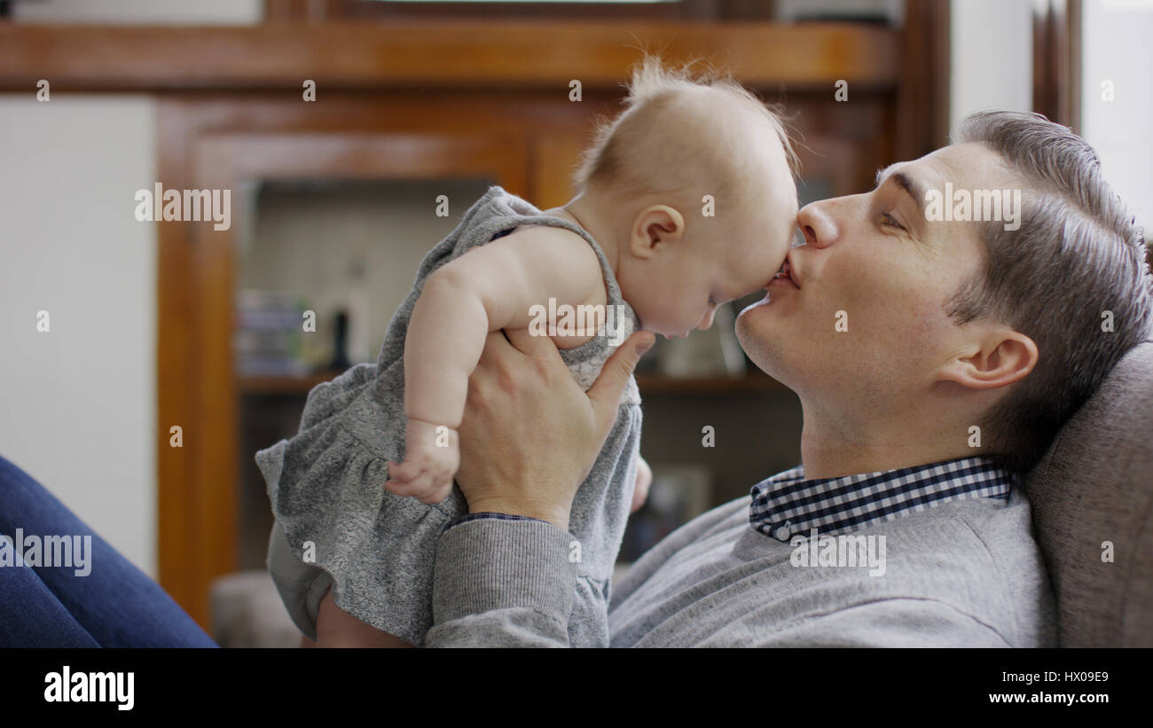 Close up profilo del padre sorridente kissing bimba di fronte sul divano Foto Stock