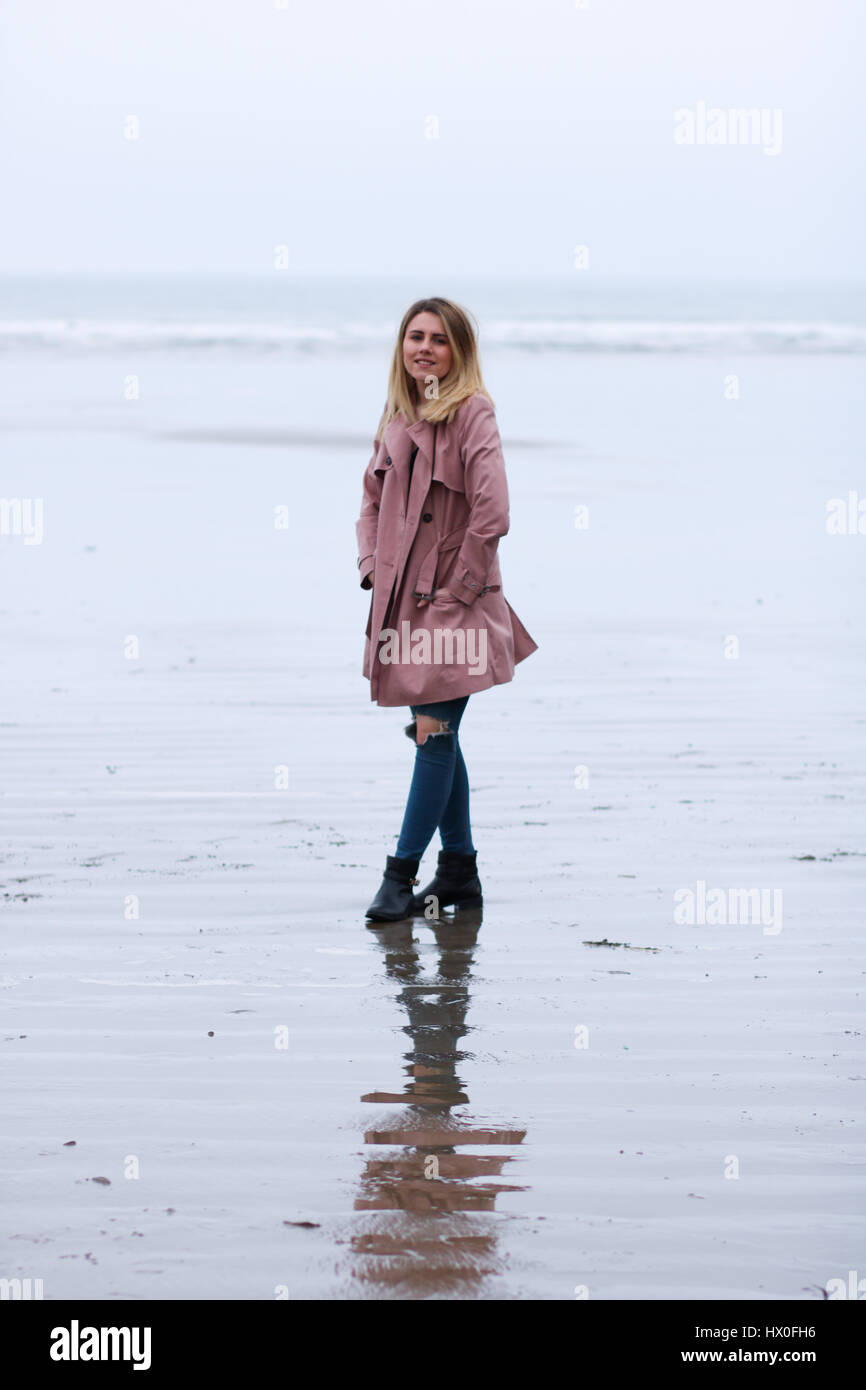 Giovane donna bionda che indossa cappotto rosa su Black Rock Sands Beach Foto Stock