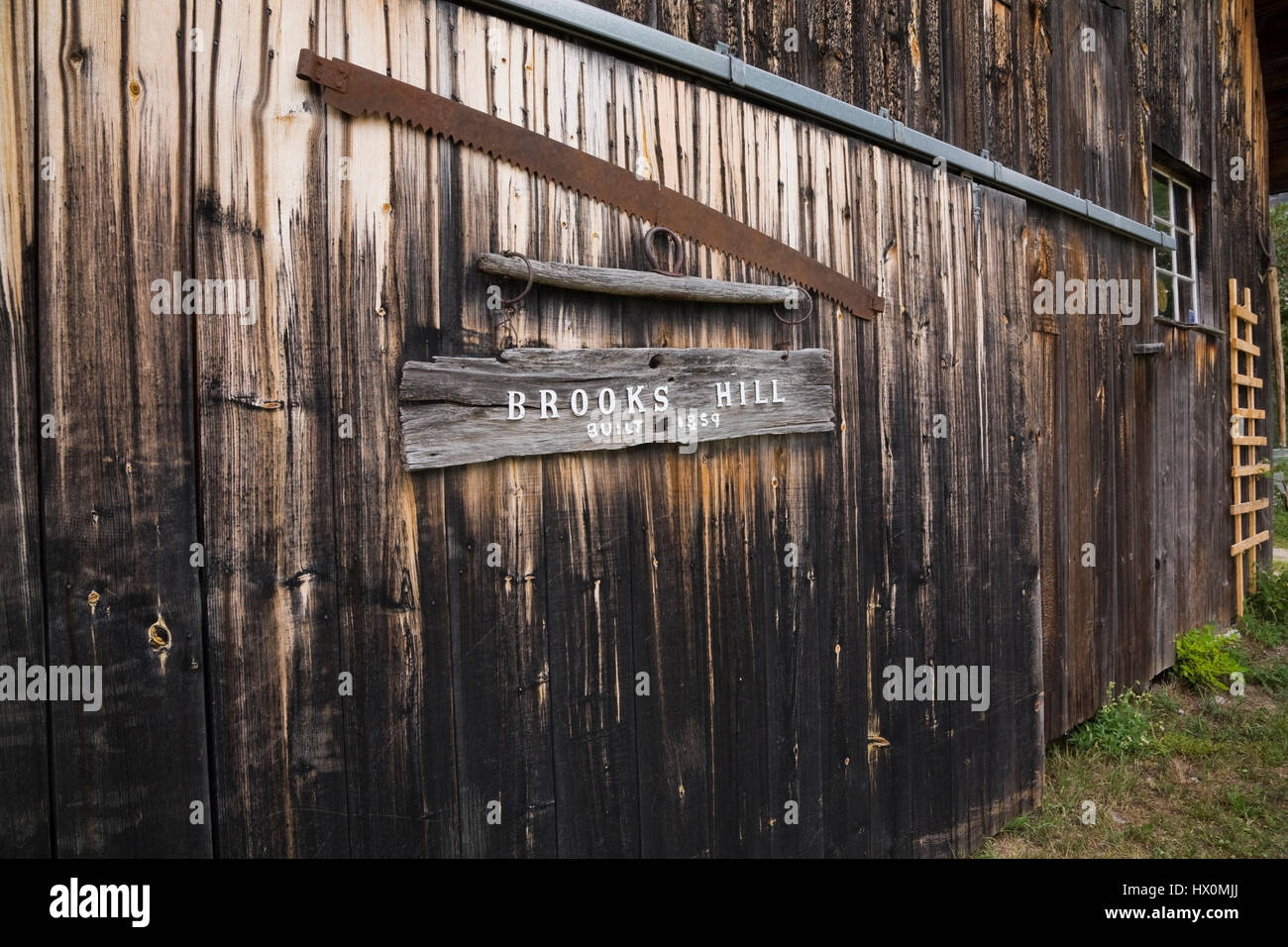 Vista parziale di un vecchio 1859 granaio in legno facciata in estate. Foto Stock