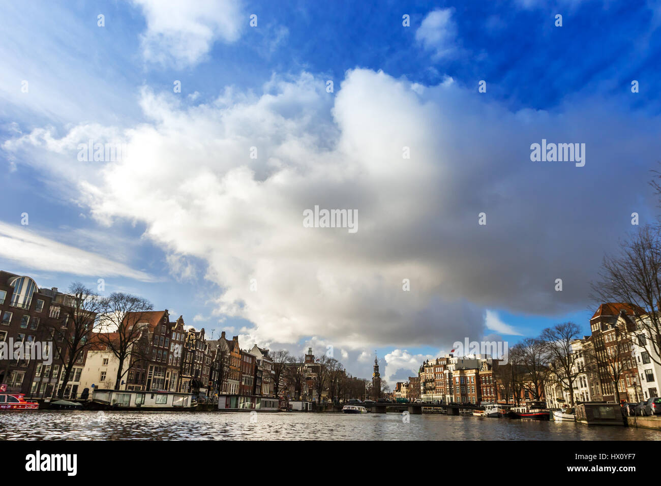 Bella vista dei canali di Amsterdam con ponti e le tipiche case fiamminga nel tempo molto soleggiato con cielo blu. Foto Stock