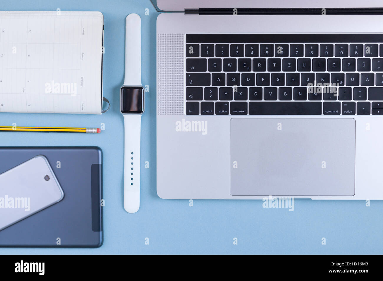 Vari dispositivi elettronici, agenda elettronica personale e una matita sulla massa blu Foto Stock