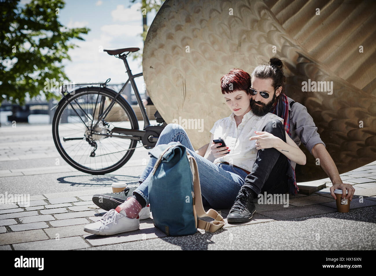Germania, Amburgo, giovane sul viaggio in bicicletta avente un resto guardando al telefono cellulare Foto Stock
