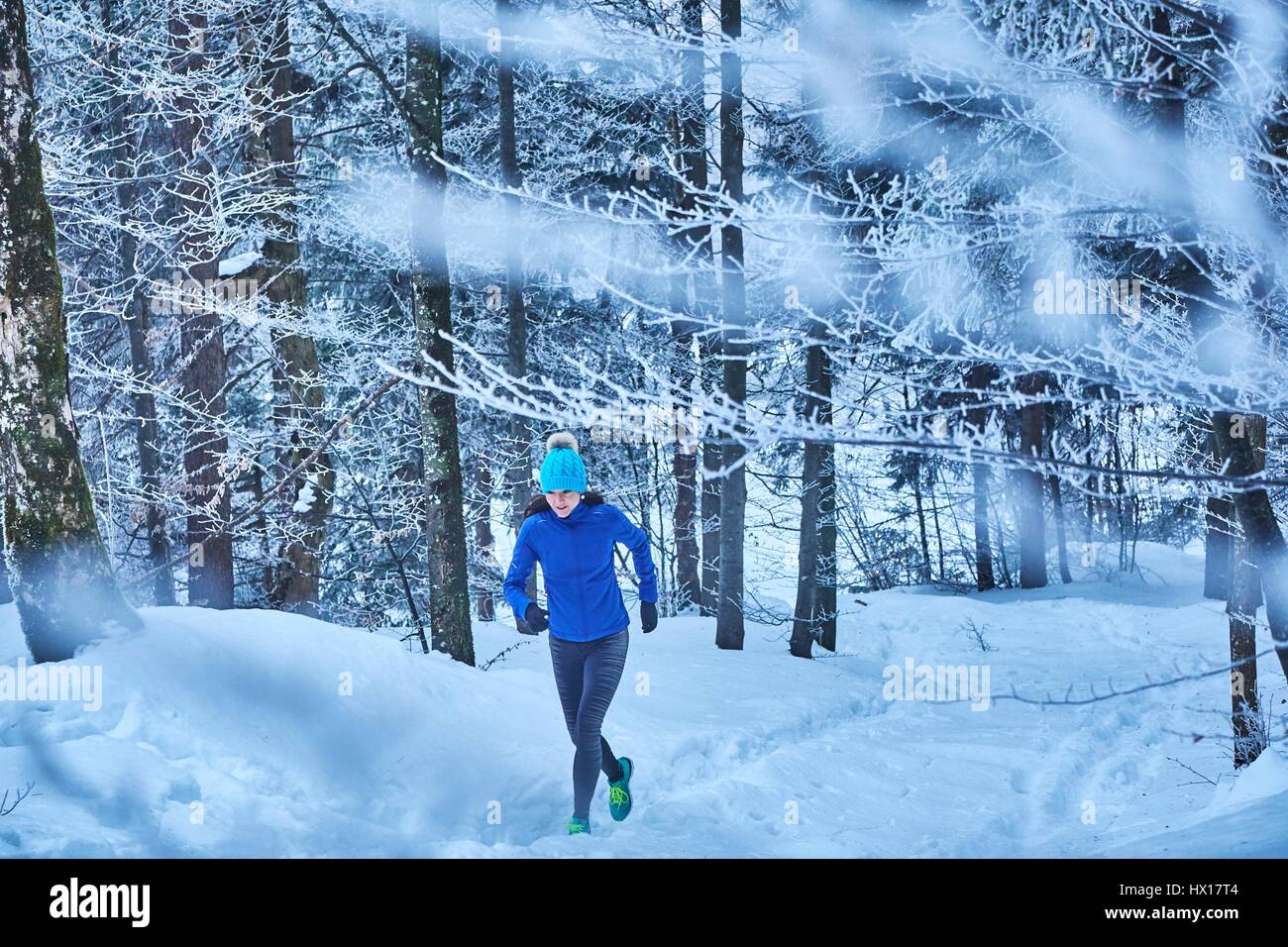 In Germania, in Baviera, Jochberg, donna jogging nel bosco invernale Foto Stock