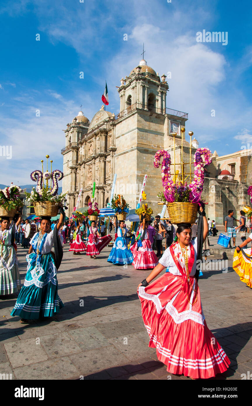 Tänzerinnen mit Blumenkörbe und Kleider bunte auf dem Hauptplatz Zocalo vor der Kathedrale, Historisches Zentrum des Weltkulturerbe Oaxaca, Mexiko Foto Stock