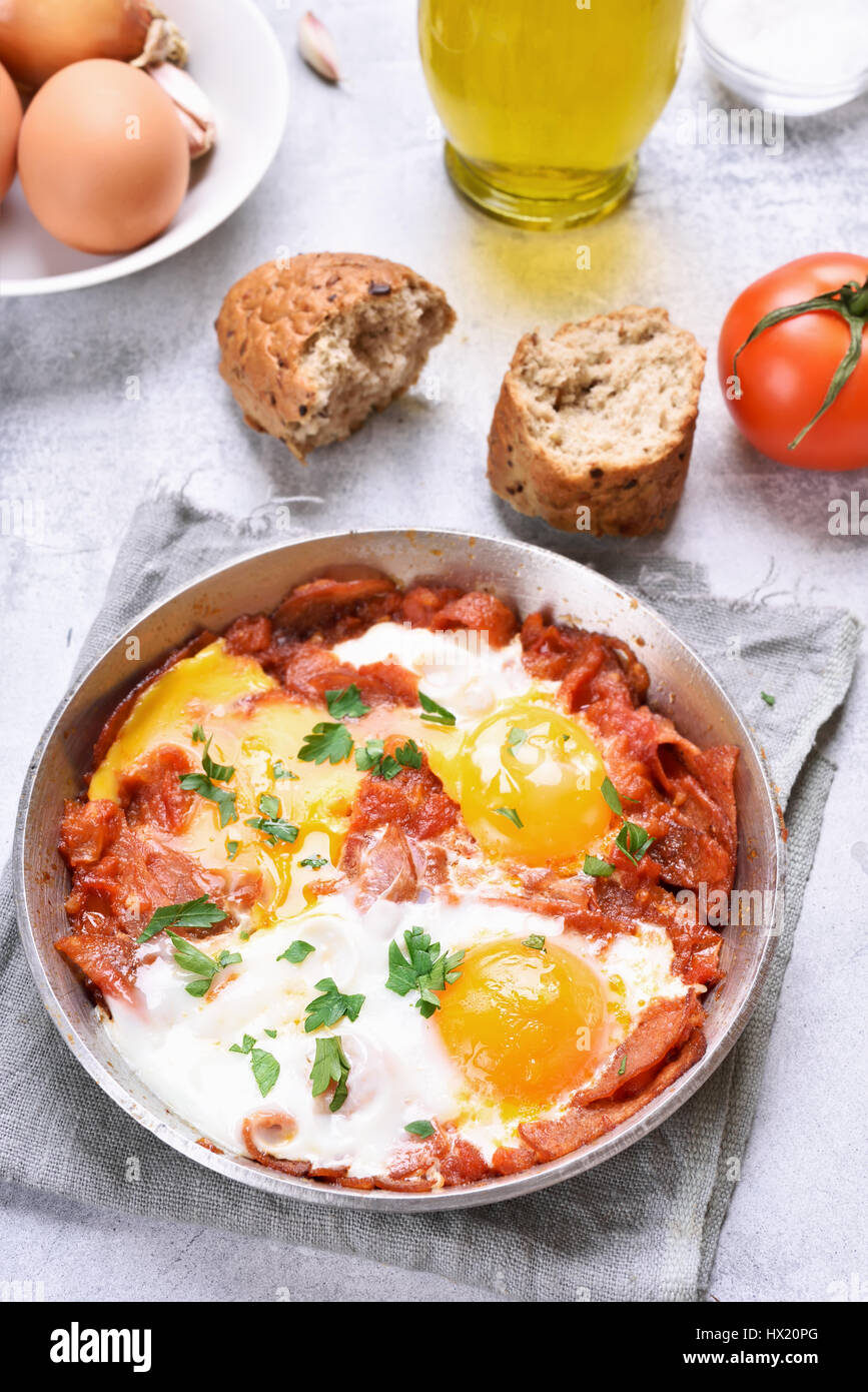 Uova fritte con pomodoro e pancetta in padella Foto Stock