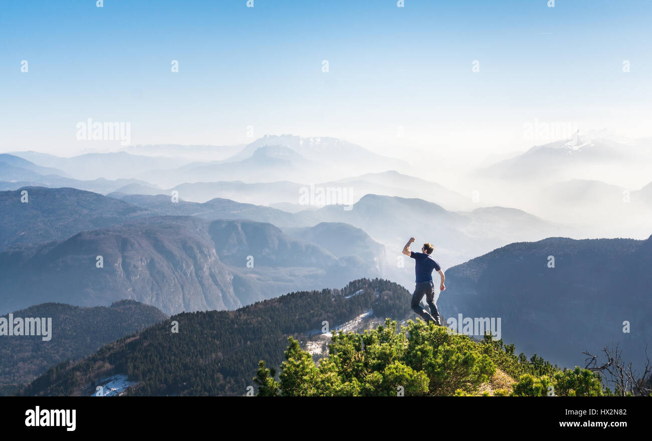 Felice successo uomo vincente sul vertice di montagna salti di gioia Foto Stock