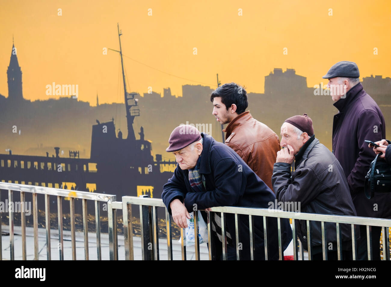 Istanbul, Turchia - 19 Febbraio 2017: vecchi e giovani uomini turco è in attesa per la nave di fronte un interessante poster a Istanbul, Turchia Foto Stock