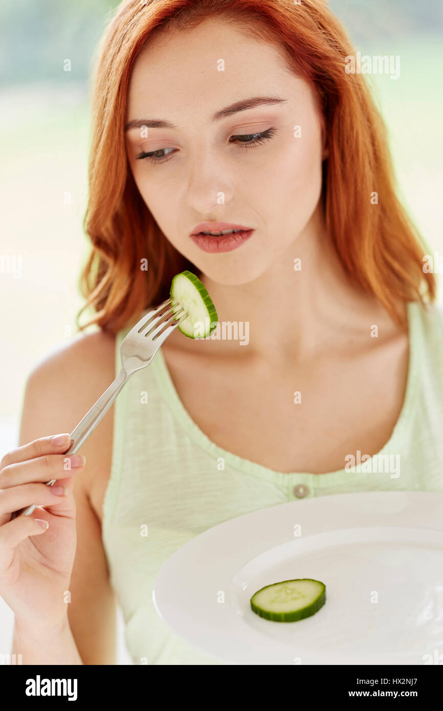 Ragazza diete mangiare fette di cetriolo Foto Stock