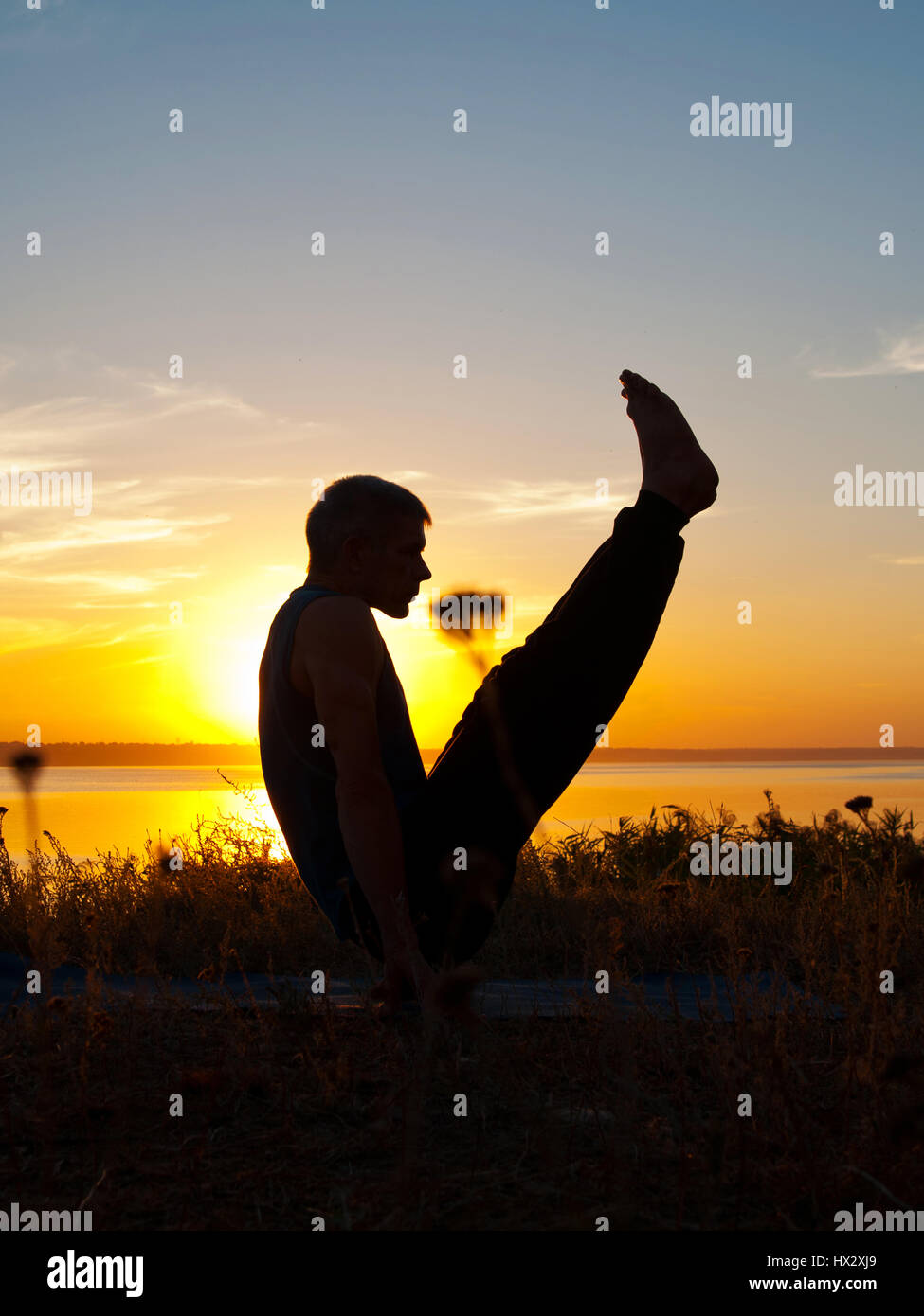 Lo Yoga atleta esegue asana al tramonto Foto Stock