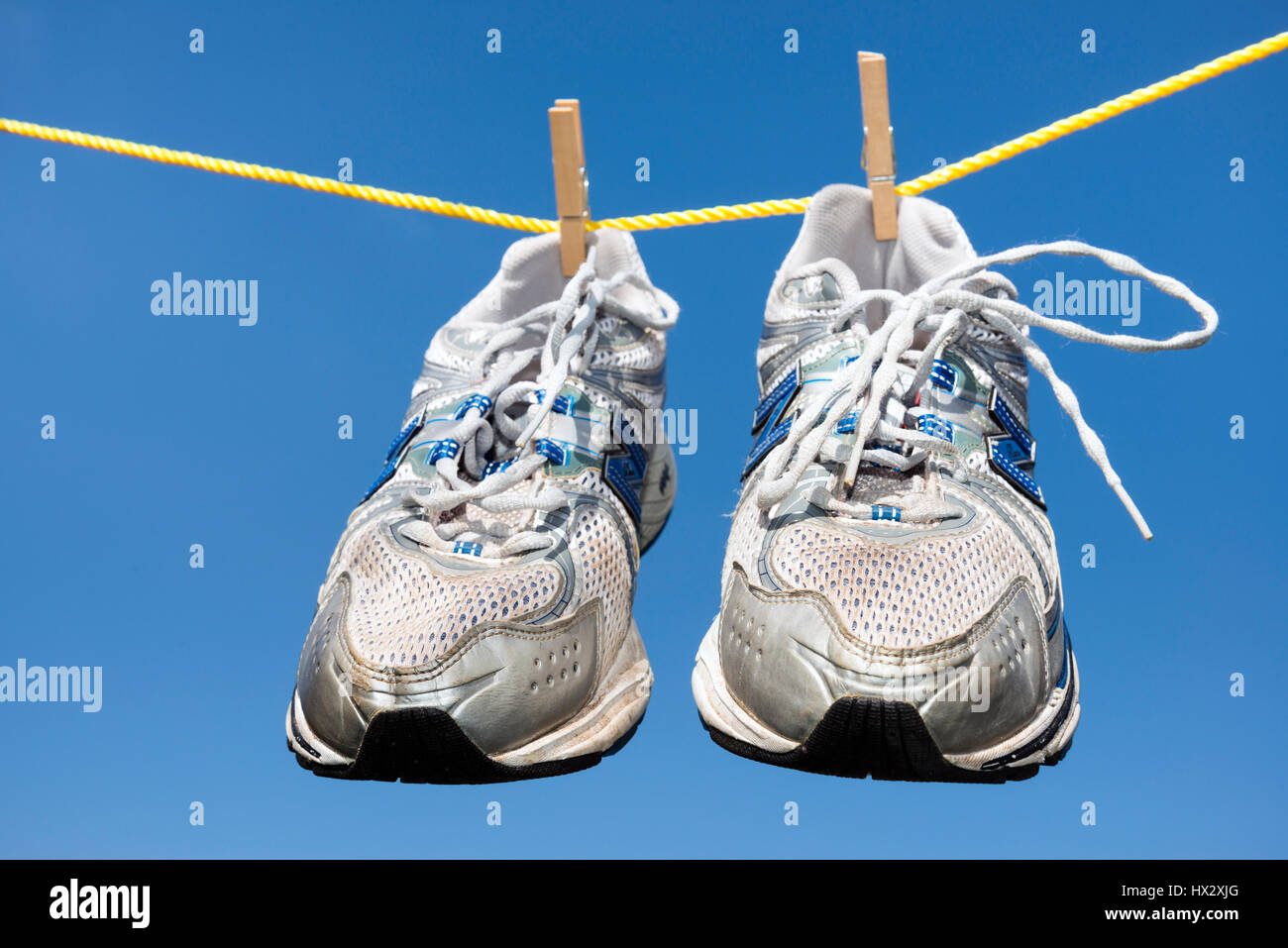 Coppia di vecchi formatori appeso su una linea di abbigliamento. Foto Stock