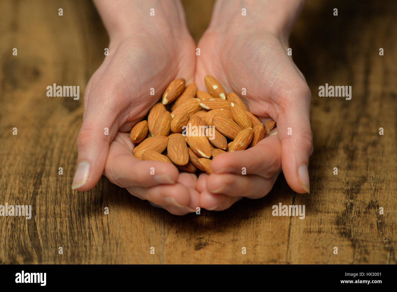 Mani tenendo un mucchio di mandorle Foto Stock