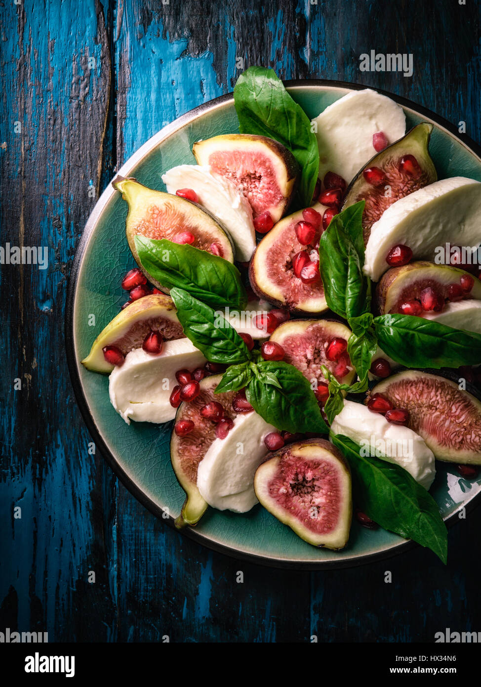 Le figure con Mozzarella di bufala e i semi di melograno su turbati da tavolo in legno Foto Stock