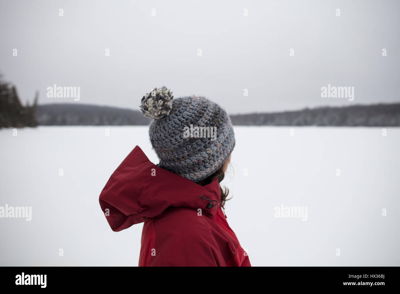 Una signora in una giacca rossa di racchette da neve dopo una tempesta di neve in Hastings Highlands, Ontario, Canada. Foto Stock