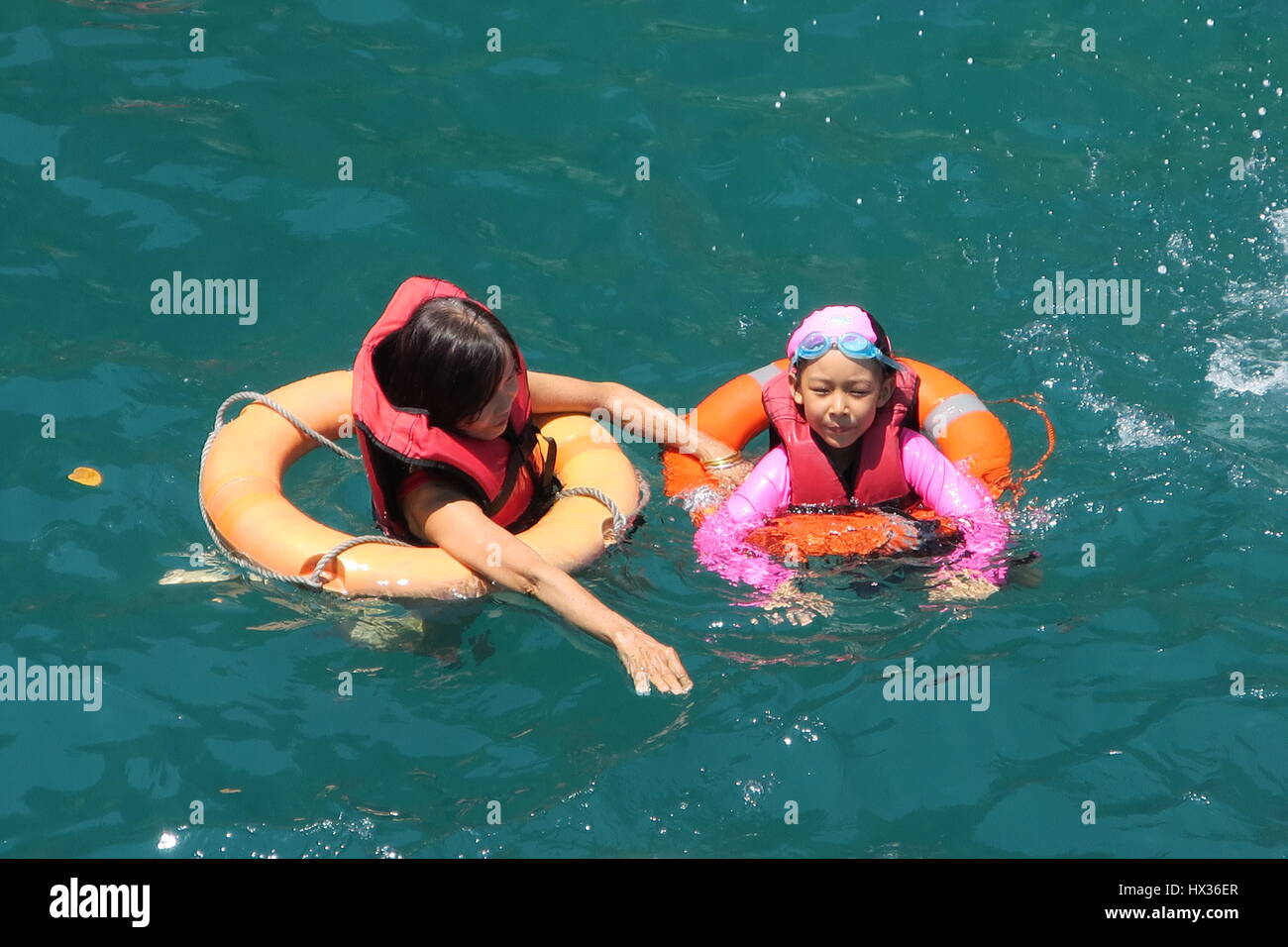 Nuotatori con la vita di giacche e giubbotti salvagente sono il nuoto e godendo di un mare pulito e caldo sul modo di Isola di Phi Phi in Thailandia. Foto Stock