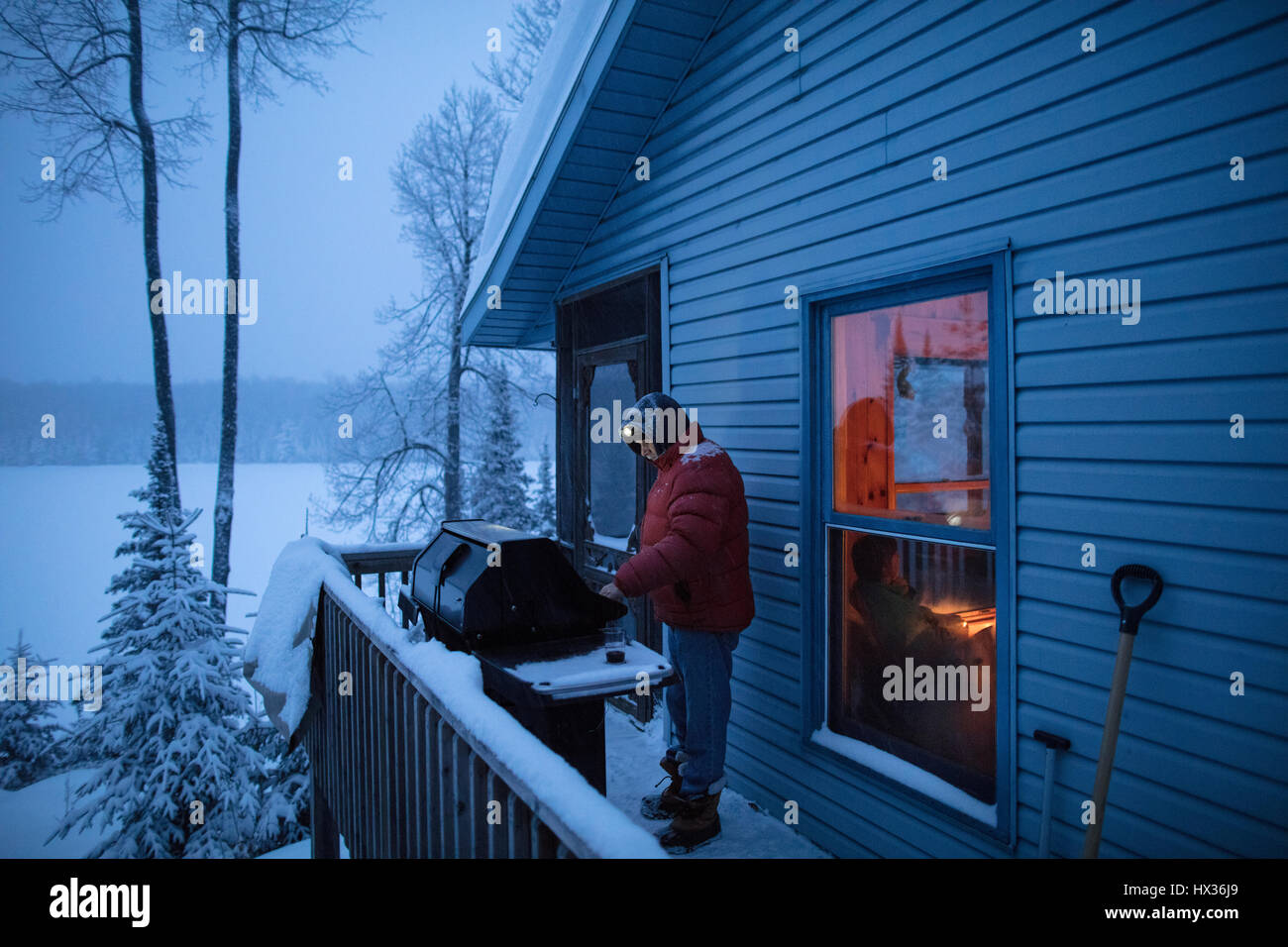 ONTARIO, Canada - 13 Febbraio 2017: un uomo barbecue / barbecue / barbecue su un nevoso inverno sera. ( Fotografo - Ryan Carter ) Foto Stock