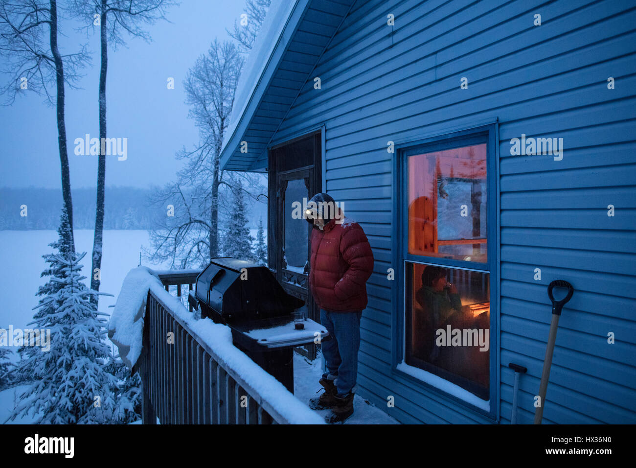 ONTARIO, Canada - 13 Febbraio 2017: un uomo barbecue / barbecue / barbecue su un nevoso inverno sera. ( Fotografo - Ryan Carter ) Foto Stock