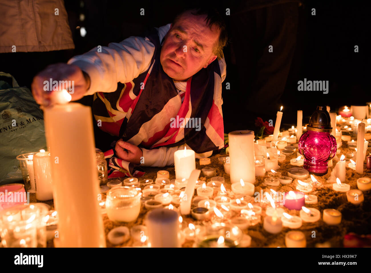 Londra, Regno Unito. 23 Mar, 2017. Un uomo aiuta a tenere sempre candele acceso in Trafalgar Square, a seguito di una veglia per ricordare le vittime del terrore di Westminster attacco. Una folla di centinaia si sono riuniti in piazza, accendendo candele e ascoltare discorsi. Credito: Giacobbe Sacks-Jones/Alamy Live News. Foto Stock