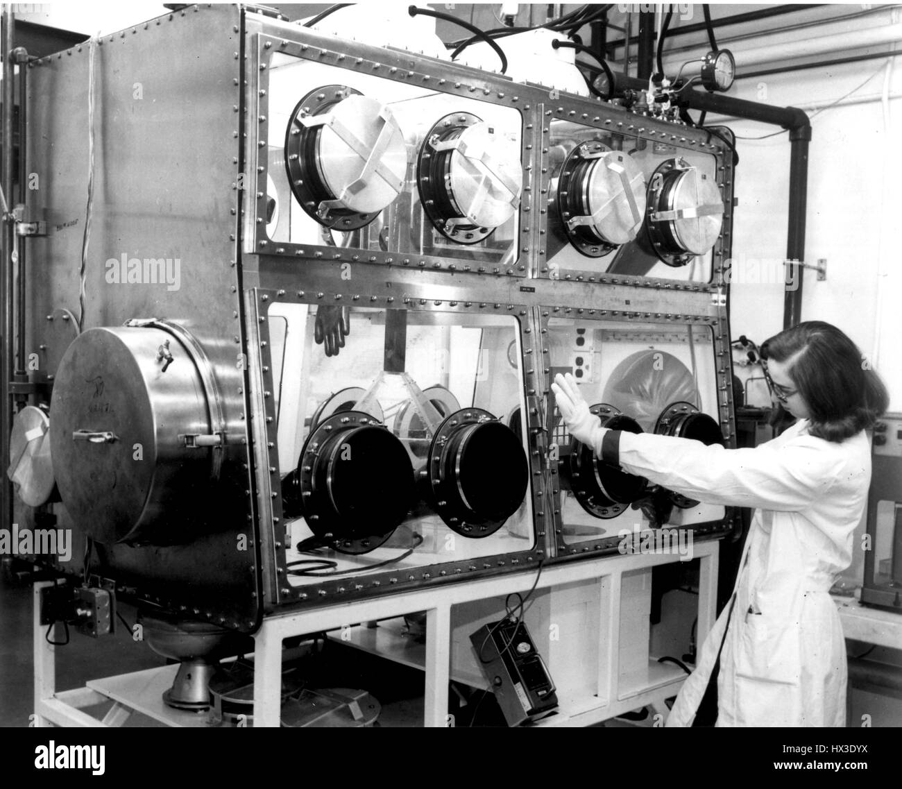 Un tecnico gestisce un campione radioattivo all'interno di un vano portaoggetti a Alpha-Gamma Struttura di Servizio nel laboratorio di caldo a Brookhaven National Laboratory di Upton, New York, 1968. Immagine cortesia del Dipartimento Americano di Energia. Foto Stock