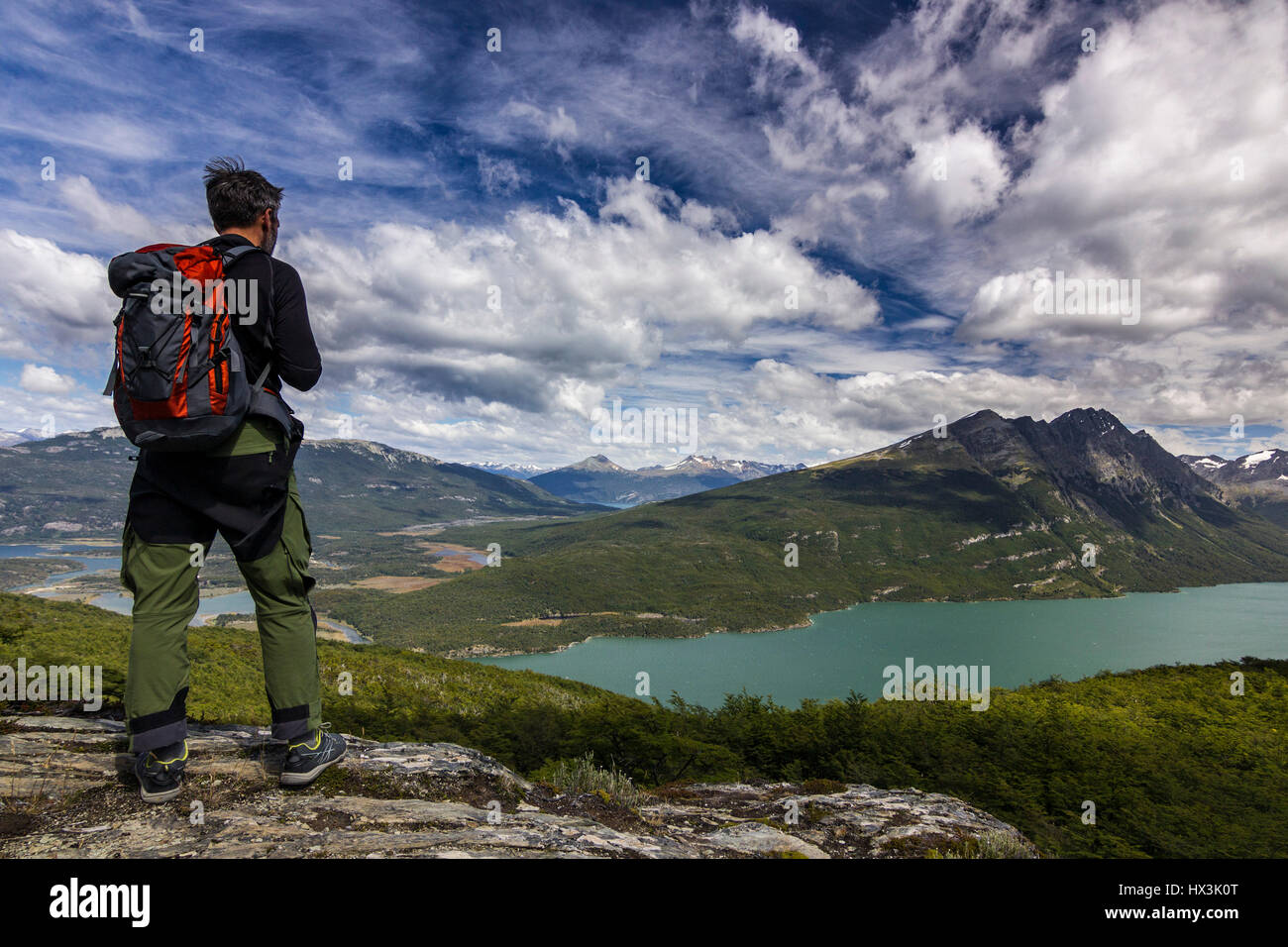 Uomo con zaino in piedi sulla rupe in montagna a sopra il lago Foto Stock