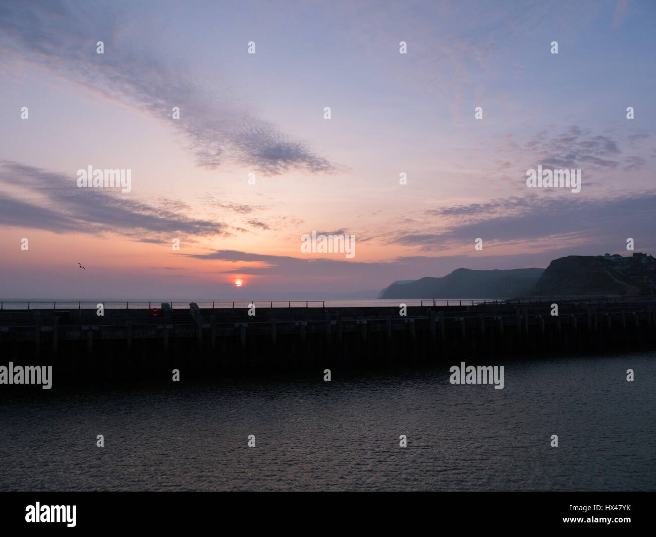 Westbay, Dorset, Regno Unito. Il 24 marzo 2017. Il cloud infine si cancella e un vago ma colorato tramonto segue. Con un meteo alto insieme a seguire e temperature più calde previsto per questo fine settimana. © Dan Tucker/Alamy Live News Foto Stock