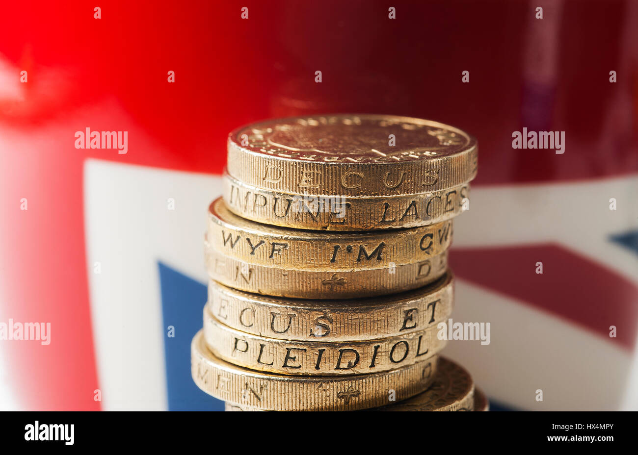 Pila di Sterling Pound monete con la bandiera europea in background Foto Stock