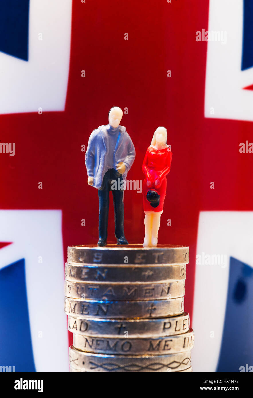 Le figure in miniatura di un uomo e di una donna in piedi sulla sterlina monete con la bandiera europea in background Foto Stock