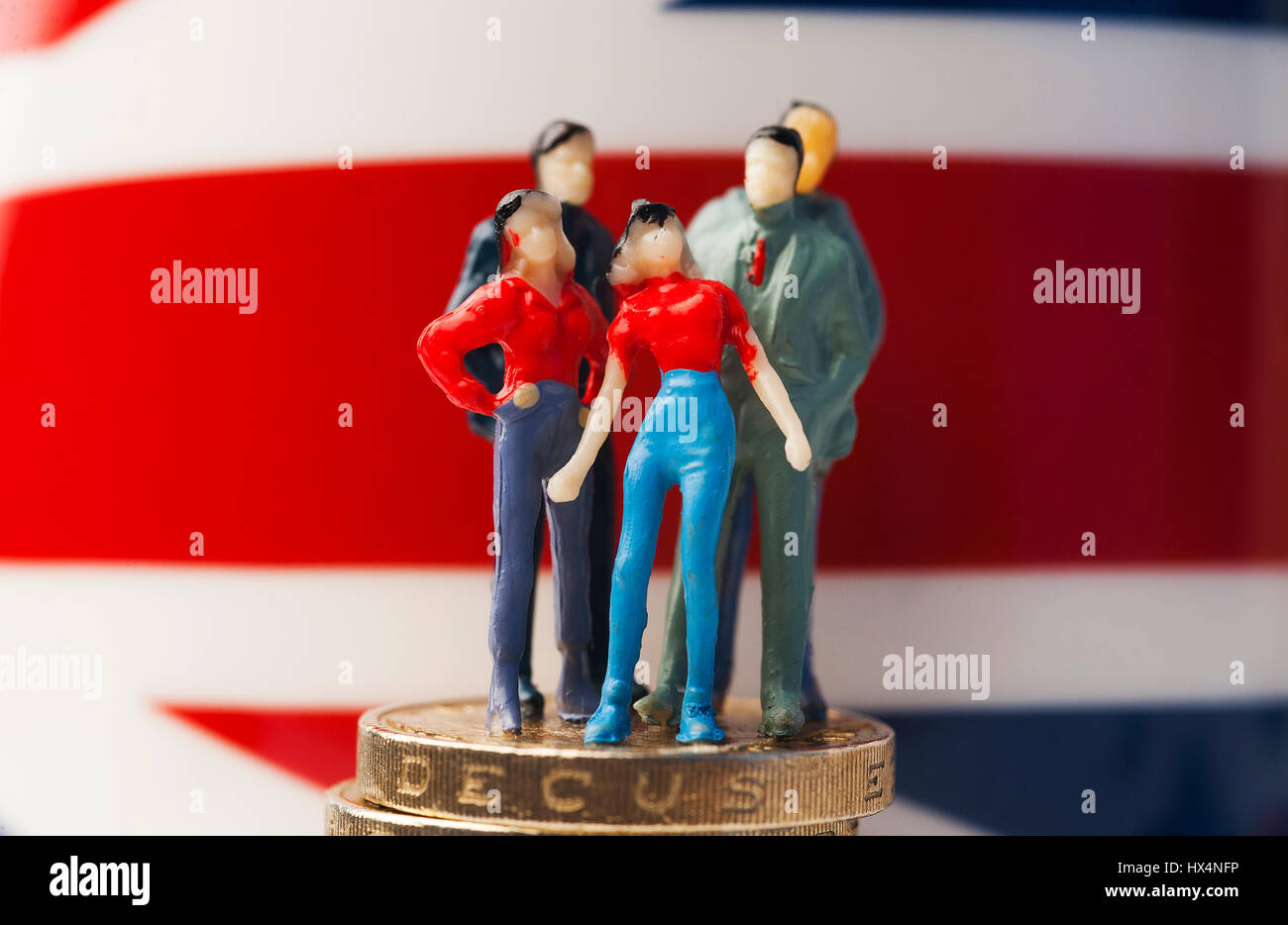 Miniatura figure di uomini e donne in piedi sulla sterlina monete con la bandiera europea in background Foto Stock