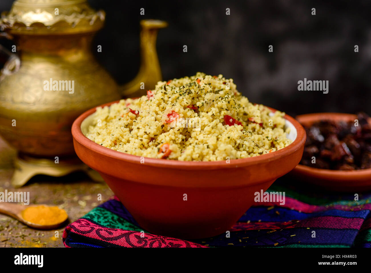 Primo piano di un vaso di terracotta con tabulé, un tipico levantine insalata araba, su di un tavolo per il pranzo o la cena con un golden teiera in backgro Foto Stock