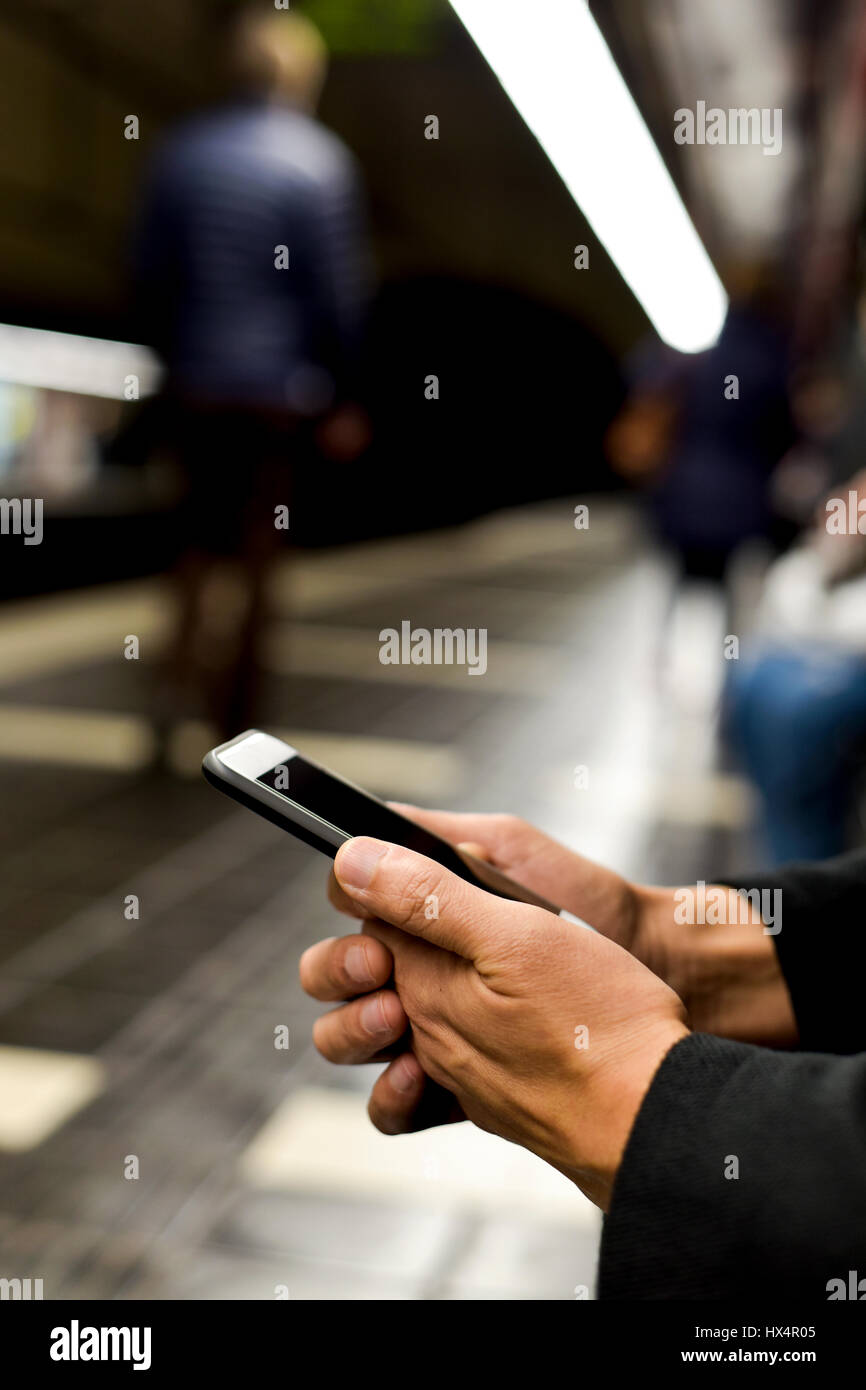 Primo piano di un giovane uomo caucasico utilizzando uno smartphone in un treno della metropolitana o tram station Foto Stock